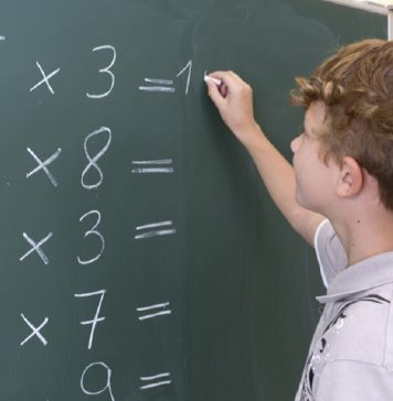 Menino escrevendo numa lousa a tabela de pitágora